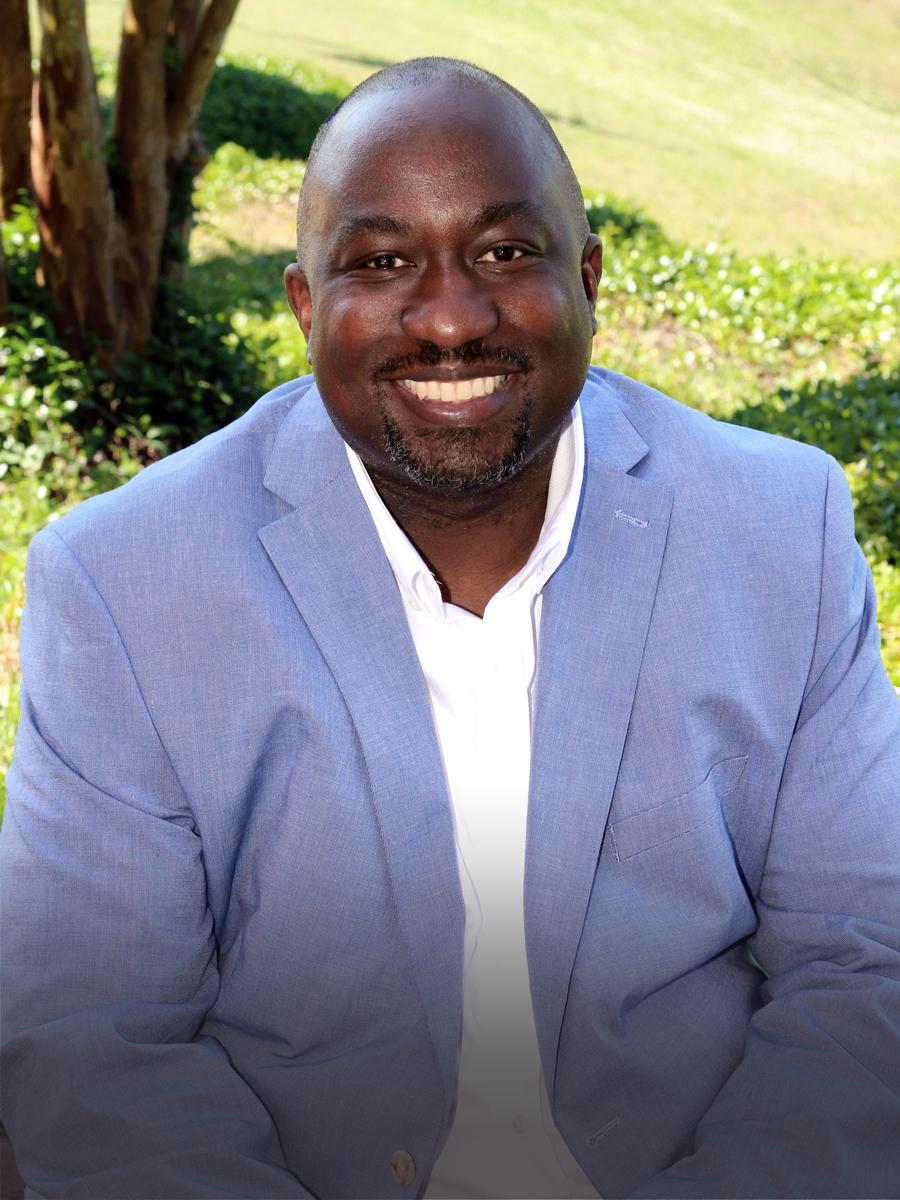 Portrait of Tim wearing a blue jacket with white shirt.