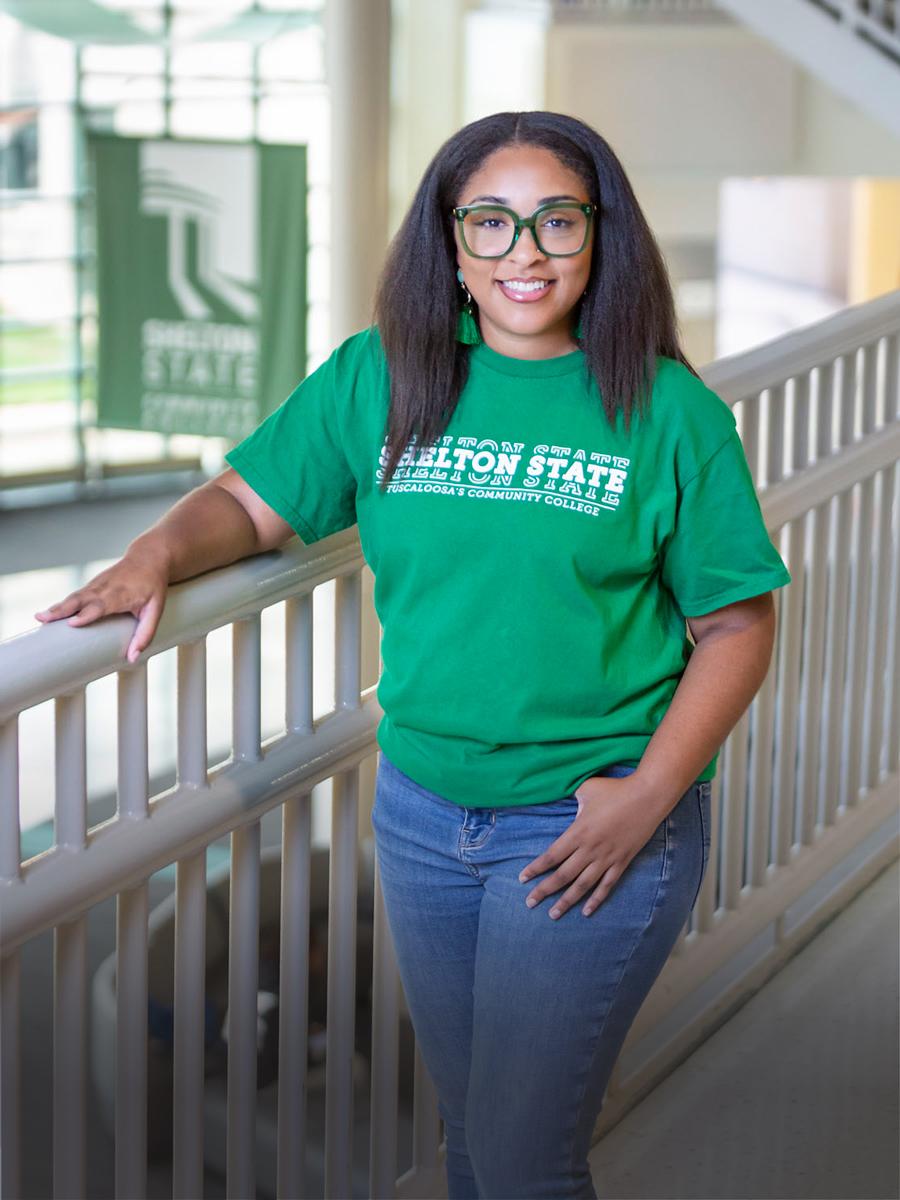 Portrait of Victoria with dark hair wearing a green shirt.